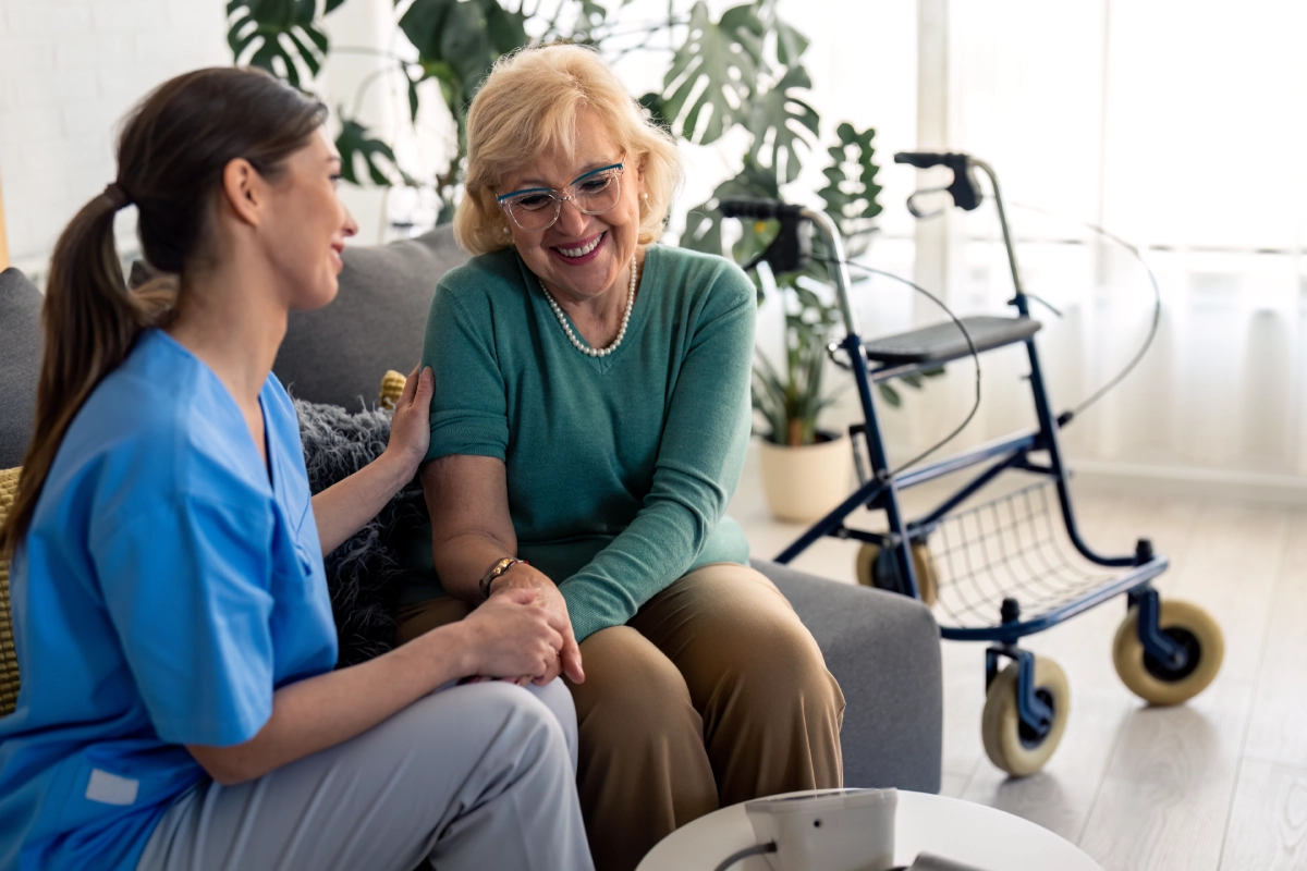 Caregiver comforting elderly woman on couch.