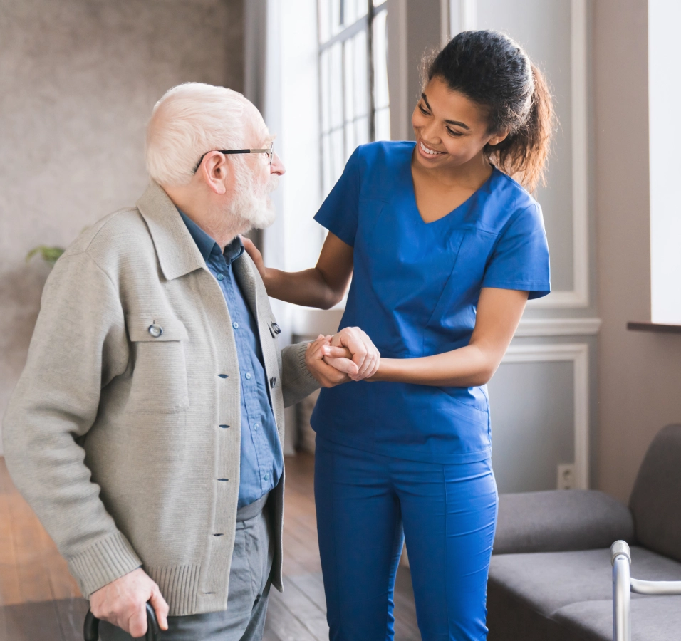 Nurse assisting elderly man with walker.